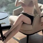 KL China Escort Amy seated in a stylish chair beside a window